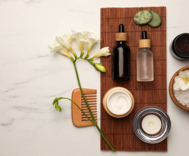 Flat lay composition with different spa products and flowers on white marble table
