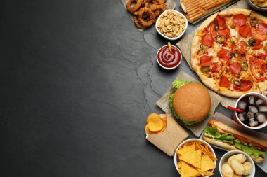 Pizza, burger ve diğer fast food 'lar siyah masada, düz uzanıyorlar mesaj için.