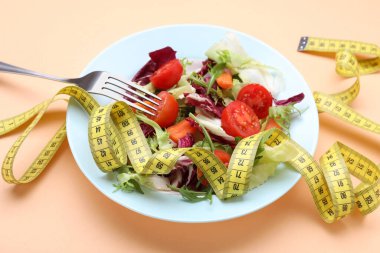 Turuncu arka planda mezuralı sağlıklı bir salata. Diyet kavramı