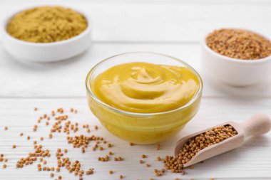 Lezzetli hardal ve tohumlarla dolu bir kase beyaz ahşap masa.