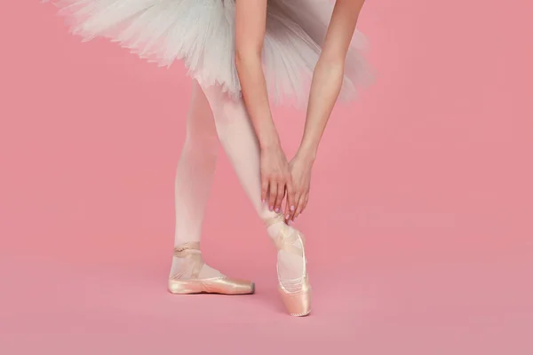 穿着尖皮鞋的年轻芭蕾舞演员在粉色背景下练习舞步 — 图库照片