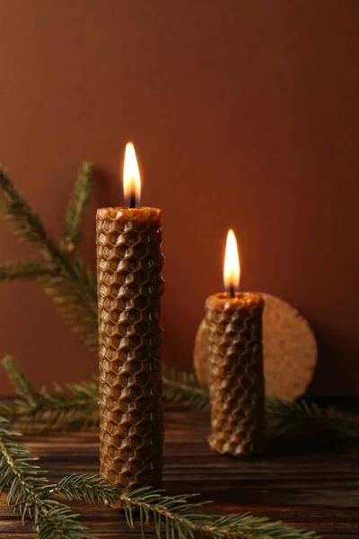 Stylish elegant beeswax candles with spruce branches on wooden table