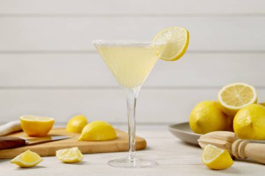 Limonlu martini kokteyli ve beyaz ahşap masada taze meyve.