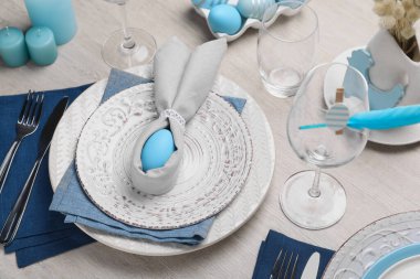 Açık mavi yumurta ve peçeteden yapılmış tavşan kulaklı şenlik masası. Paskalya kutlaması