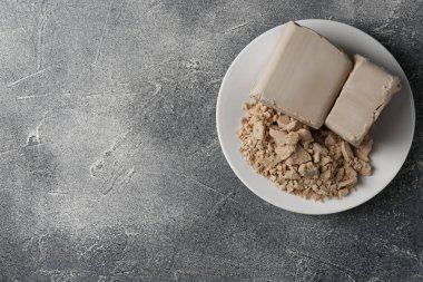 Compressed yeast on grey table, top view. Space for text