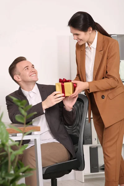 stock image Woman presenting gift to her colleague in office