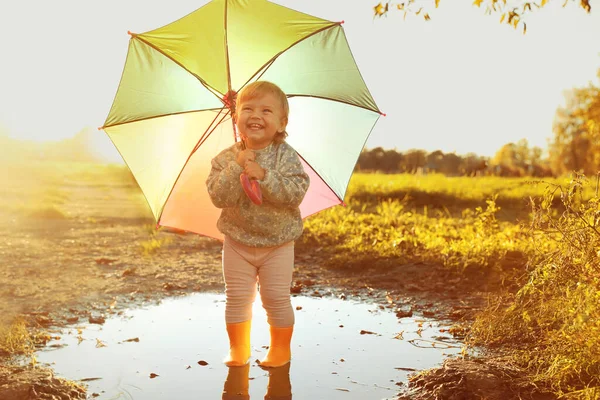 屋外の水たまり テキストのためのスペースでカラフルな傘でゴムブーツを身に着けている女の子 秋の散歩 — ストック写真