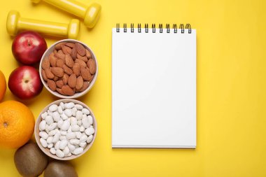 Not defteri, sarı arka planda taze meyve ve badem, düz yatak. Düşük glisemik indeks diyeti