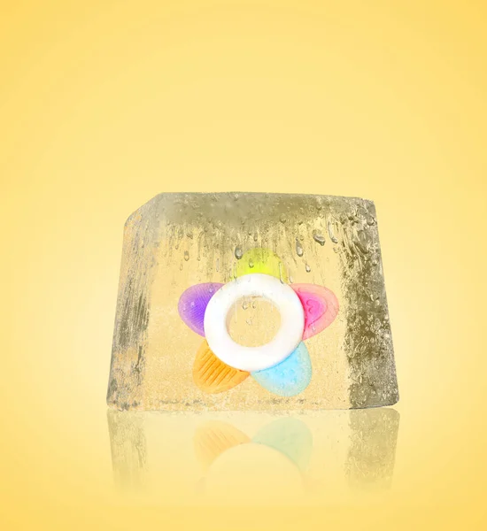 Conservation of genetic material. Baby teether in ice cube as cryopreservation on yellow background