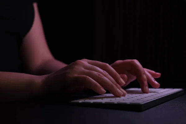 Woman using computer in dark room, closeup. Internet addiction