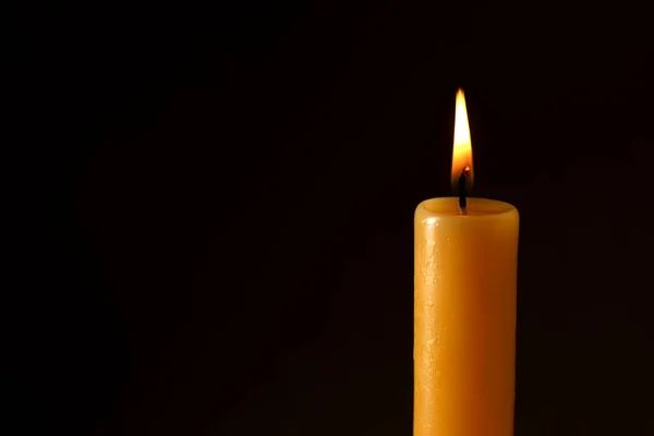 Burning church wax candle on dark background, closeup. Space for text