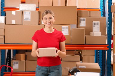 Post office worker with parcel near rack indoors