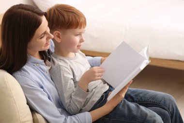 Anne evde çocuğuyla kitap okuyor.