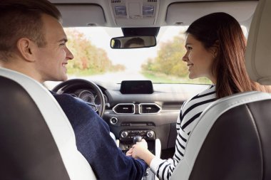 Mutlu genç çift arabayla seyahat ediyor.