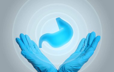 Mide ekşimesinin ve diğer gastrointestinal hastalıkların semptomları. Açık gri arkaplanda mide çizimi tutan doktor, yakın plan.