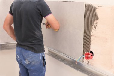 Kapalı alanda fayans yerleştirmek için vakum plakası kullanan işçiler
