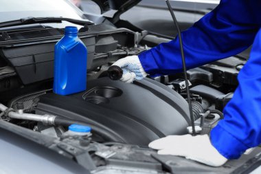 İşçi, arabadaki motor yağı seviyesini kontrol ediyor.