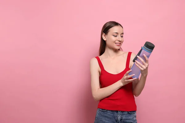 ピンクの背景に透明なボトルを持つ美しい若い女性 テキストのためのスペース — ストック写真