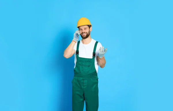Professionele Reparateur Uniform Praten Smartphone Tegen Lichtblauwe Achtergrond — Stockfoto