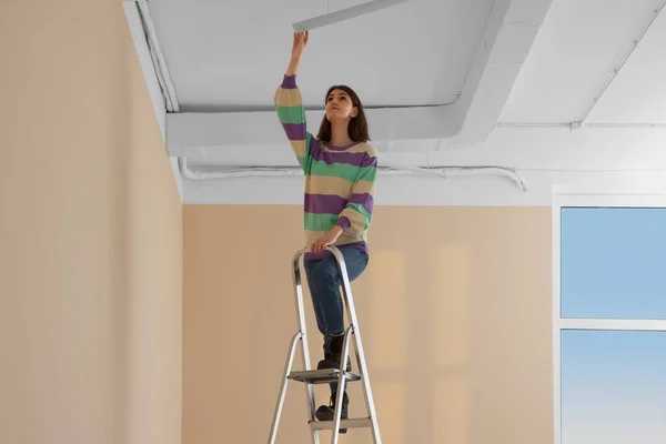 Junge Frau Installiert Deckenlampe Auf Leiter Haus Raumsanierung — Stockfoto