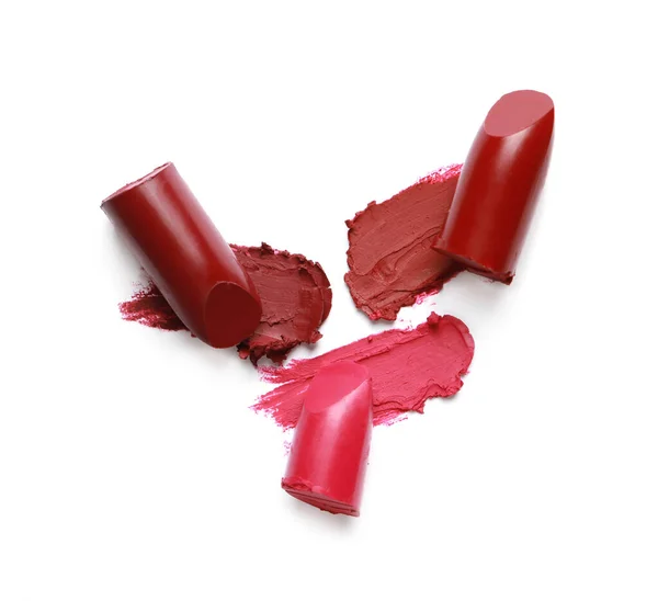 Different lipsticks and smears on white background, top view