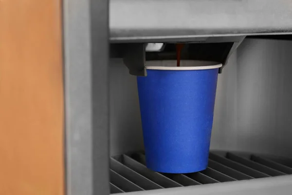 Vending machine pouring coffee in paper cup, closeup
