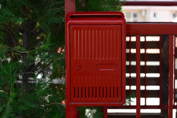 Red beautiful metal letter box near tree outdoors