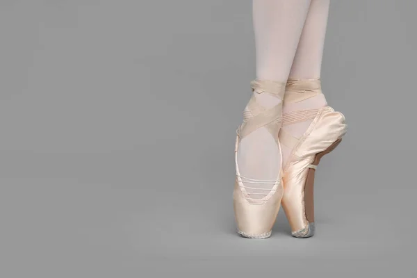 穿着尖皮鞋的年轻芭蕾舞演员在灰色背景下练习跳舞 案文的篇幅 — 图库照片