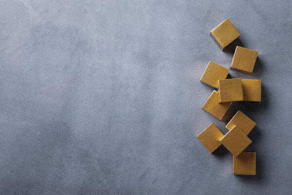 Golden cubes on grey table, flat lay. Space for text