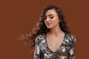 Kahverengi arka planda uzun kıvırcık saçlı, güzel bir kadın.