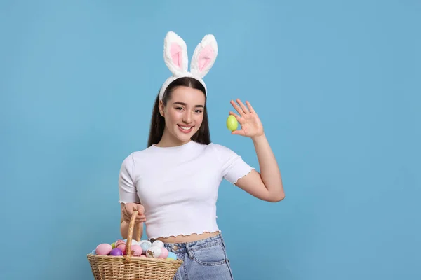 快乐的女人 戴着兔子耳朵的头带 手里拿着一篮子绿松石背景彩绘复活节彩蛋 案文的篇幅 — 图库照片