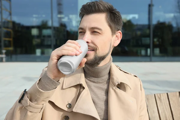 Handsome man drinking from tin can outdoors