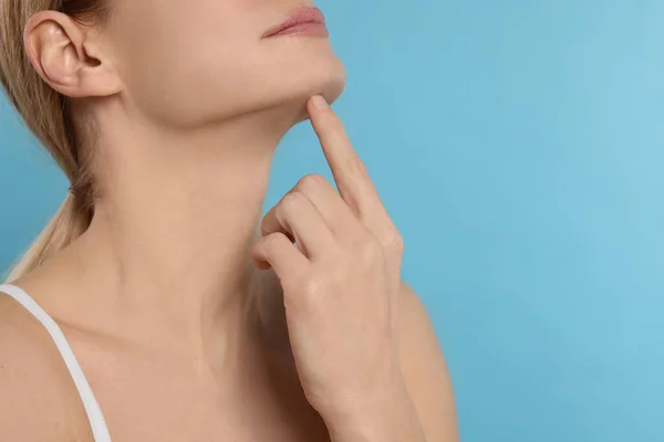 stock image Woman massaging her face on turquoise background, closeup. Space for text