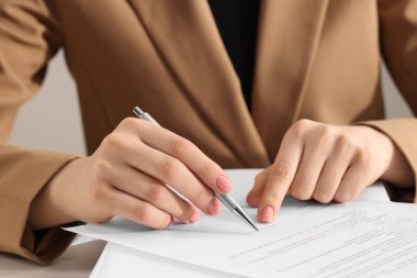 Woman signing document at table, closeup view