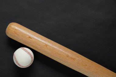 Wooden baseball bat and ball on black background, flat lay. Space for text