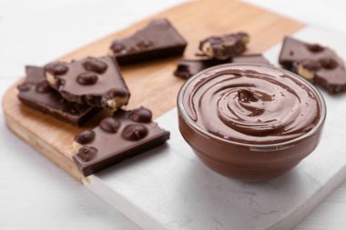 Lezzetli bir tutkal ve beyaz ahşap masada çikolata parçaları, yakın plan.