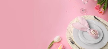 Yumurtadan yapılmış tavşan kulakları ve pembe arka planda peçeteyle süslü Paskalya sofrası. Metin için alanı olan pankart tasarımı