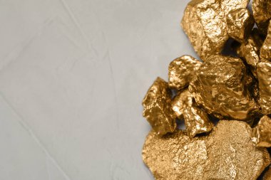 Pile of gold nuggets on light grey table, flat lay. Space for text