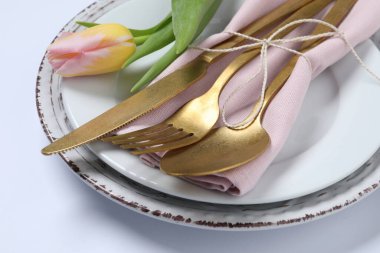 Beyaz arka planda çatal bıçak ve lale ile şık masa ayarları, yakın plan