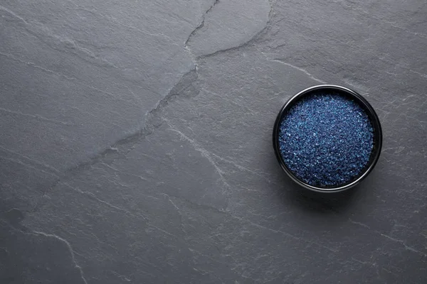 Bowl of blue food coloring on grey table, top view. Space for text