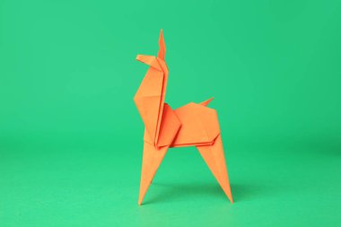 Origami sanatı. Yeşil arka planda el yapımı turuncu kağıt geyik