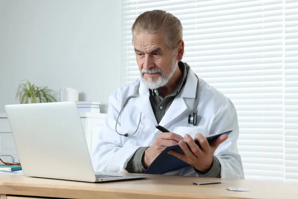 Médico Sênior Com Laptop Prancheta Consulta Paciente Mesa Madeira Clínica — Fotografia de Stock