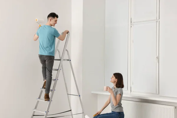 Hombre Joven Pintando Pared Escalera Mientras Mujer Tomando Café Interior — Foto de Stock