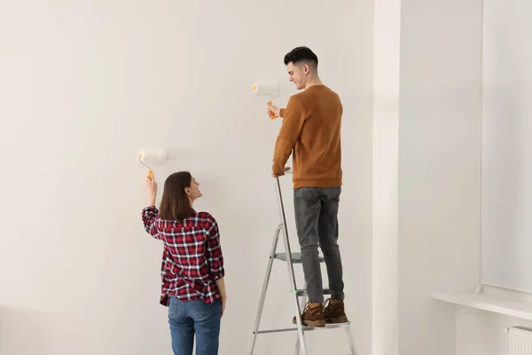 年轻夫妇在室内用滚筒粉刷墙壁 房间翻新 — 图库照片