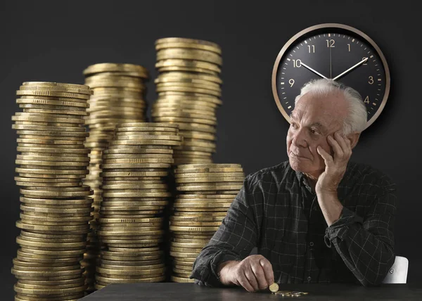 Pension plan. Elderly man with coins on dark background