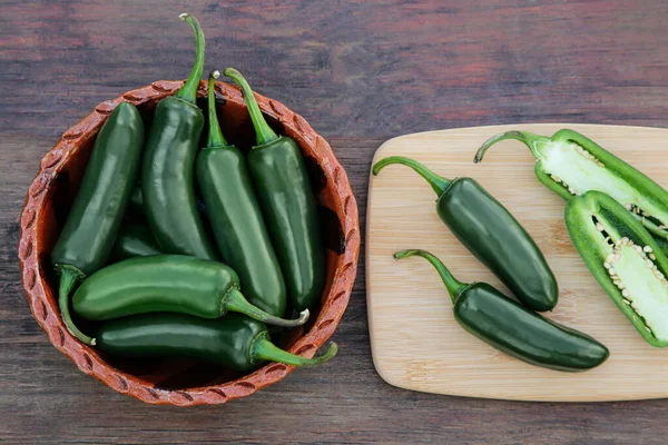 Whole and cut jalapeno peppers on wooden table, flat lay
