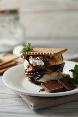 Beyaz ahşap masada kraker ve çikolatalı leziz marshmallow sandviçi.