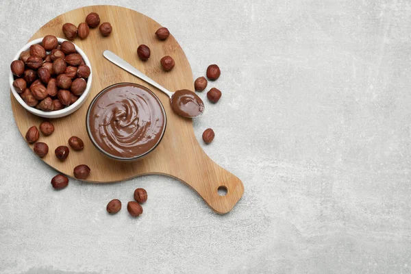 Bowl with tasty chocolate paste and nuts on light grey table, flat lay. Space for text