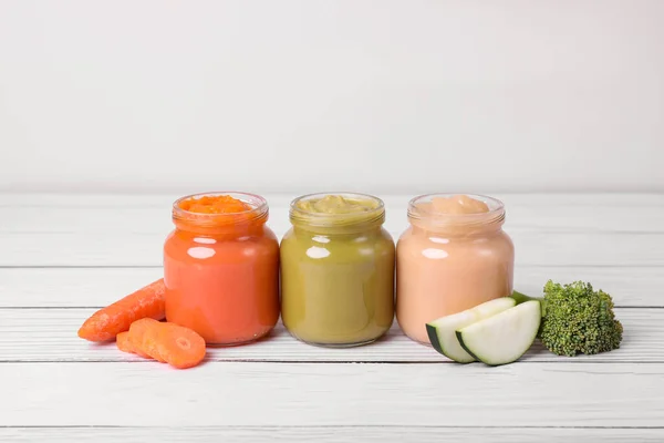 stock image Jars of healthy baby food and vegetables on white wooden table