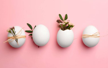 Chicken eggs and natural decor on pink background, flat lay. Happy Easter